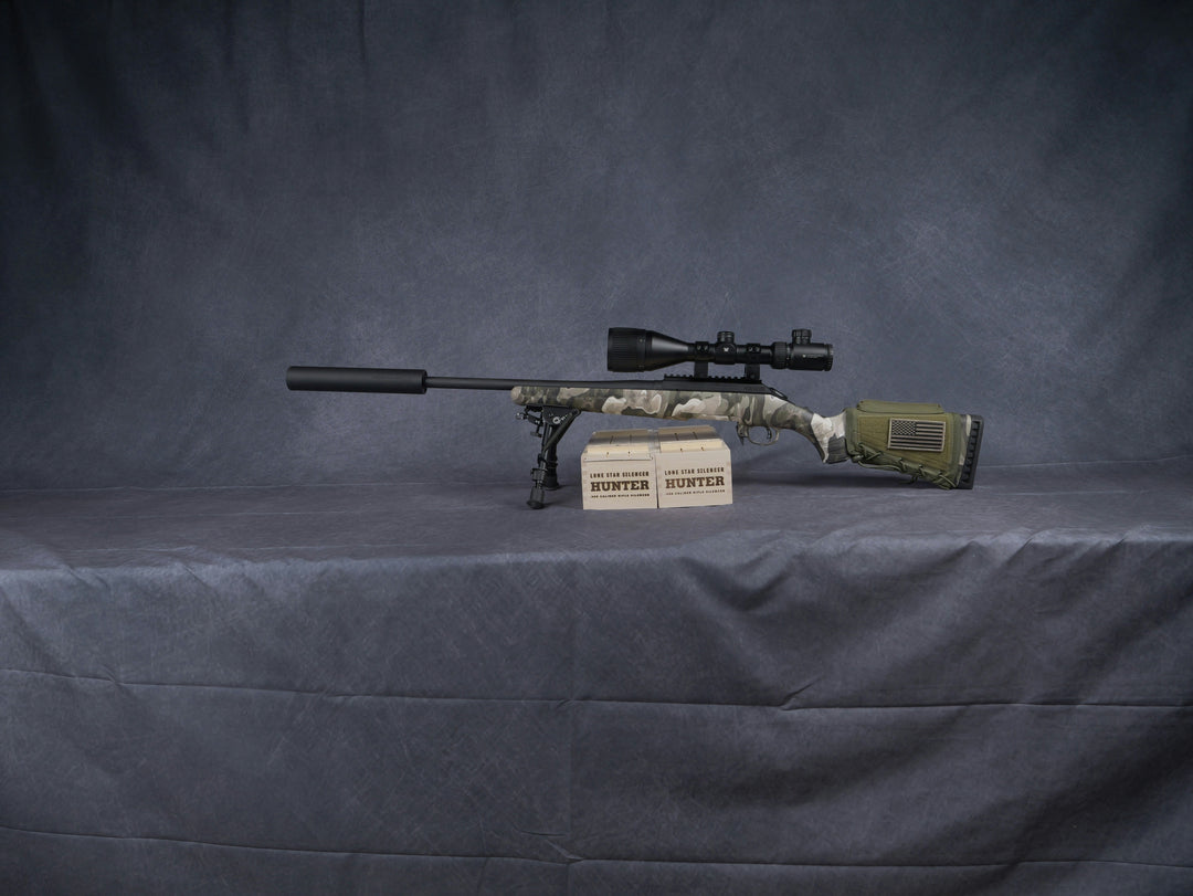 Camouflaged hunting rifle with scope and sound moderator fitted